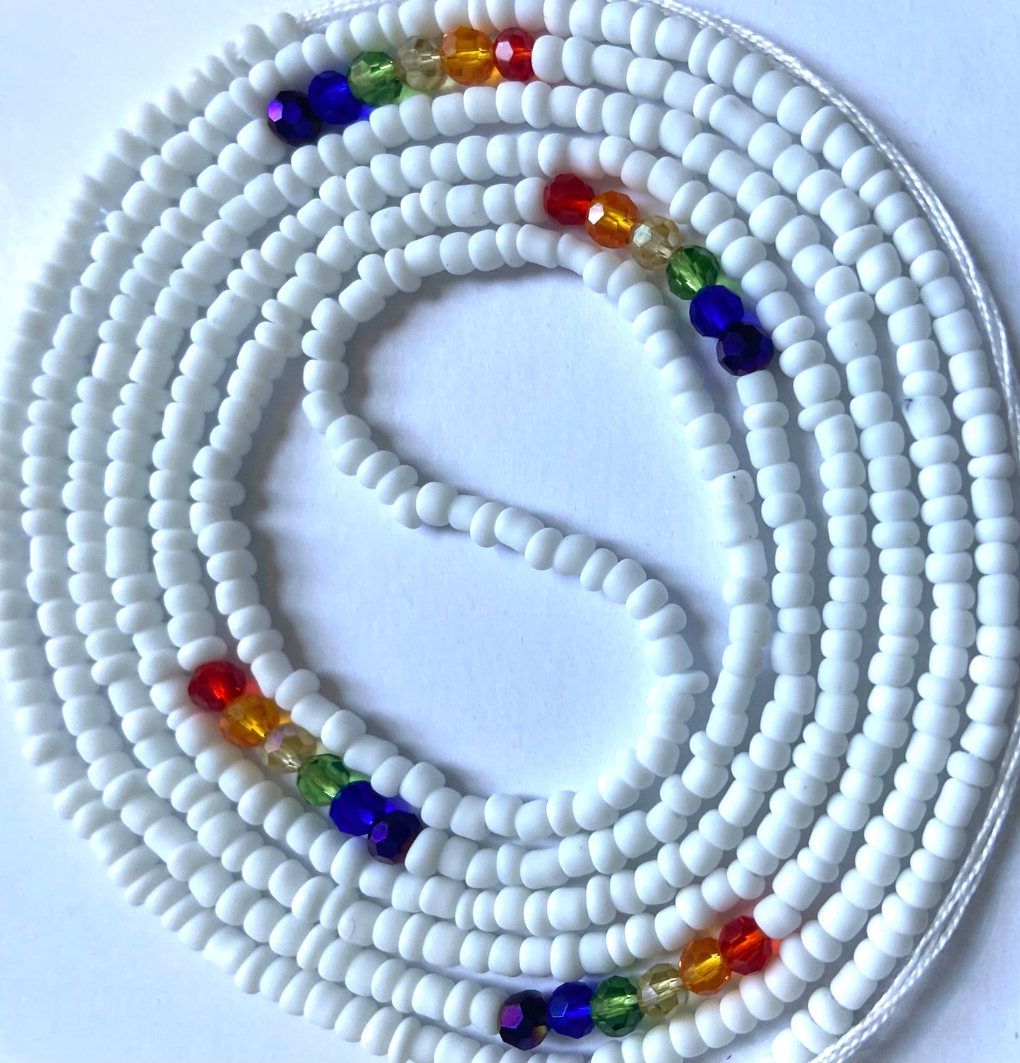 White seed beads with red orange yellow green blue and purple crystals